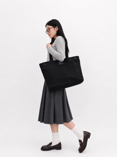 Woman wearing a carbon black canvas laptop tote over her shoulder