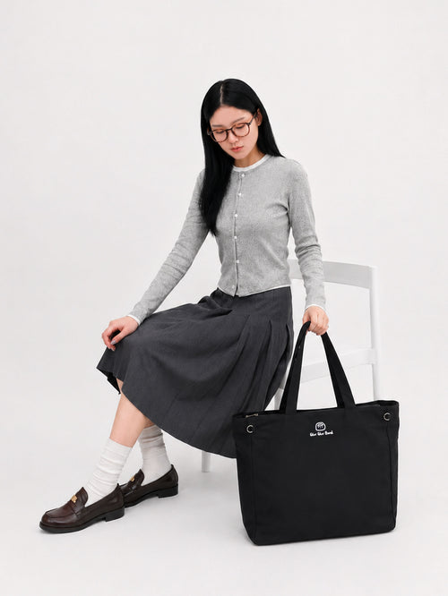 Woman seated beside a carbon black canvas laptop tote bag for work