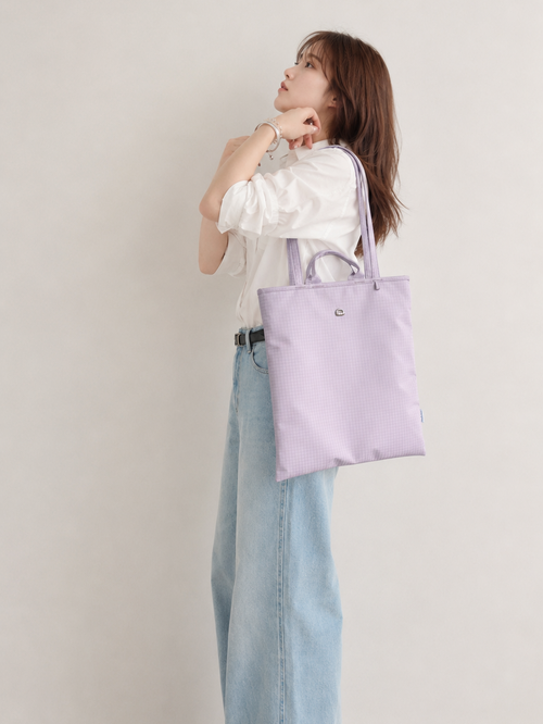 Woman wearing a light purple vertical laptop tote over her shoulder