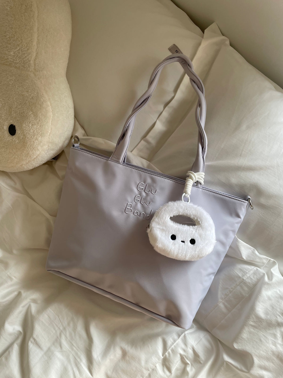 White character coin pouch styled on a lavender tote on soft bedding; coin pouch only